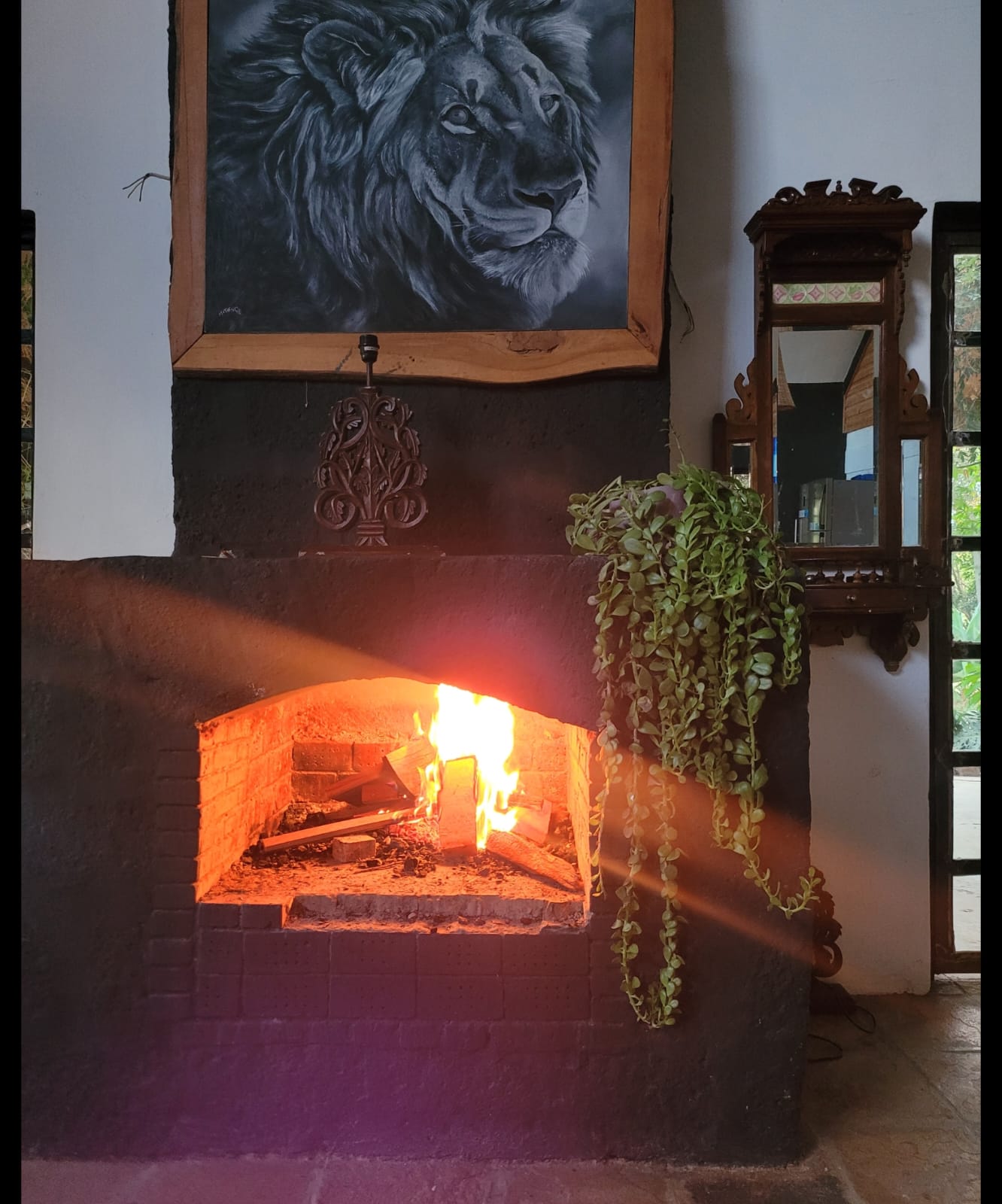 Indoor fireplace burning below lion artwork and a vintage wall mirror.